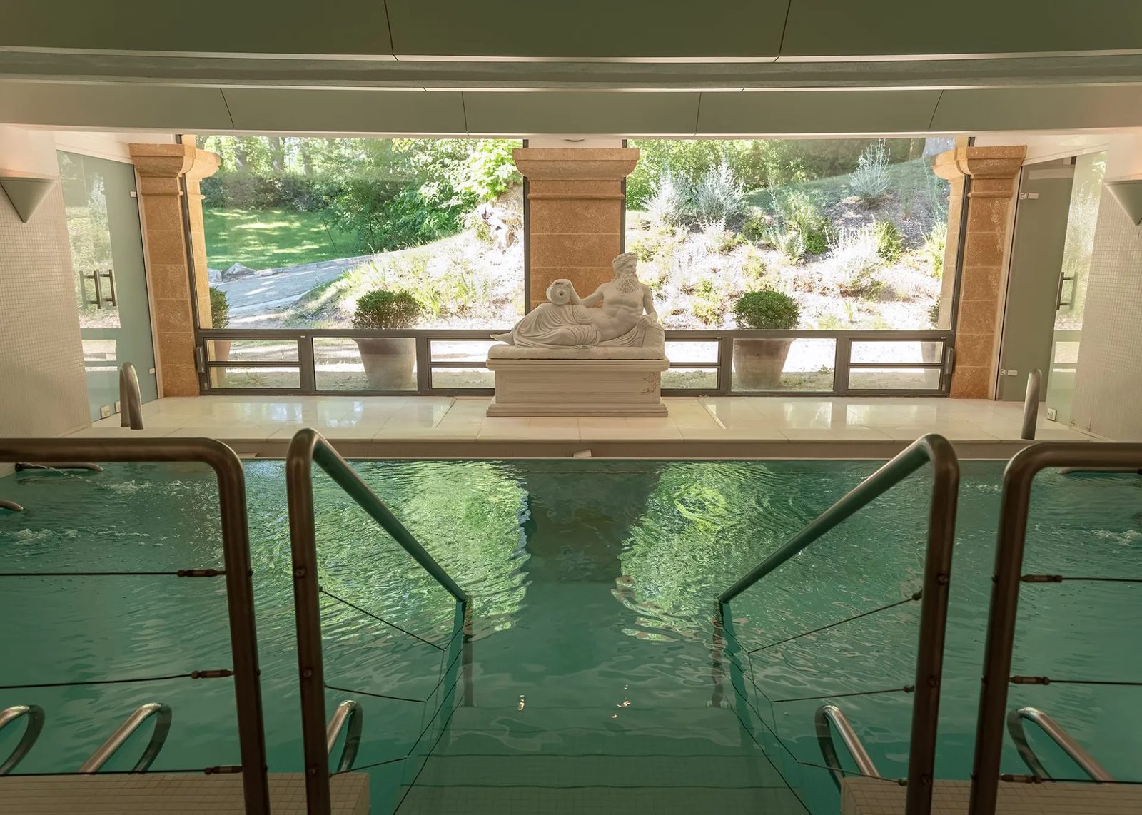 Bassin thermal intérieur des Thermes de Gréoux ouvert sur le jardin, avec sa statue antique