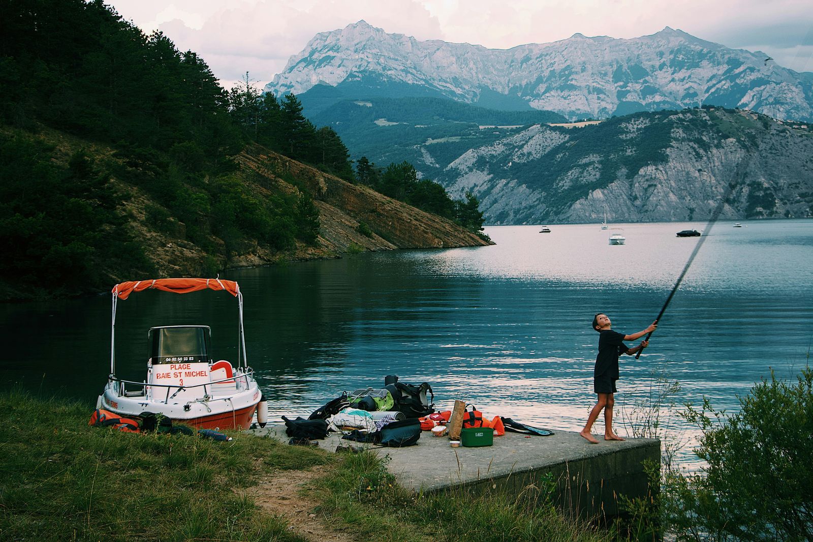 Pêche au bord d'un lac de Haute-Provence au coucher du soleil, montagnes en arrière-plan
